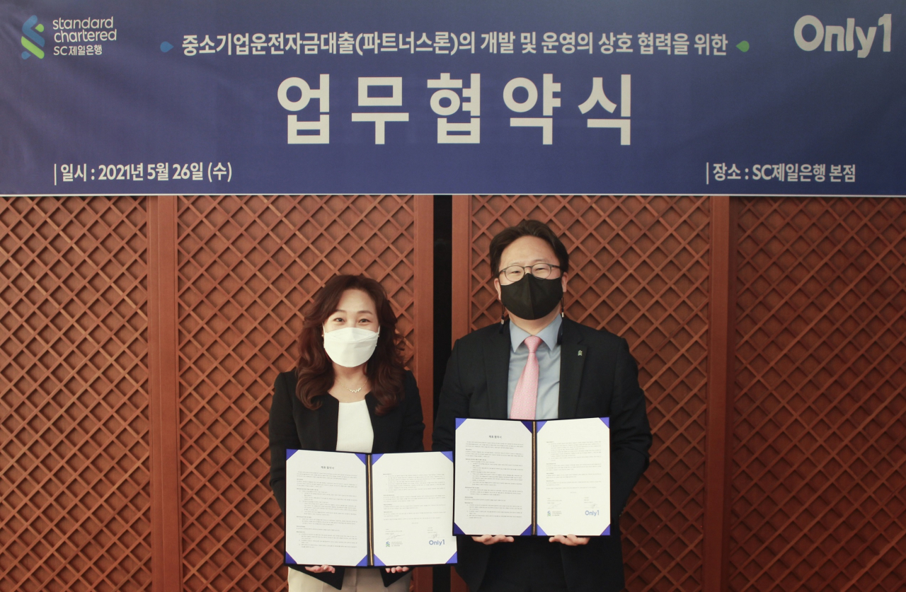 지난 26일 서울 종로구 SC제일은행 본사에서 열린 ‘중소기업운전자금대출(파트너스론)의 개발 및 운영의 상호 협력을 위한 업무협약식’에서 장호준 SC제일은행 소매금융총괄본부장(부행장·오른쪽)이 최성진 ㈜온리원 CEO와 함께 협약서에 서명하고 기념촬영을 하고 있다.