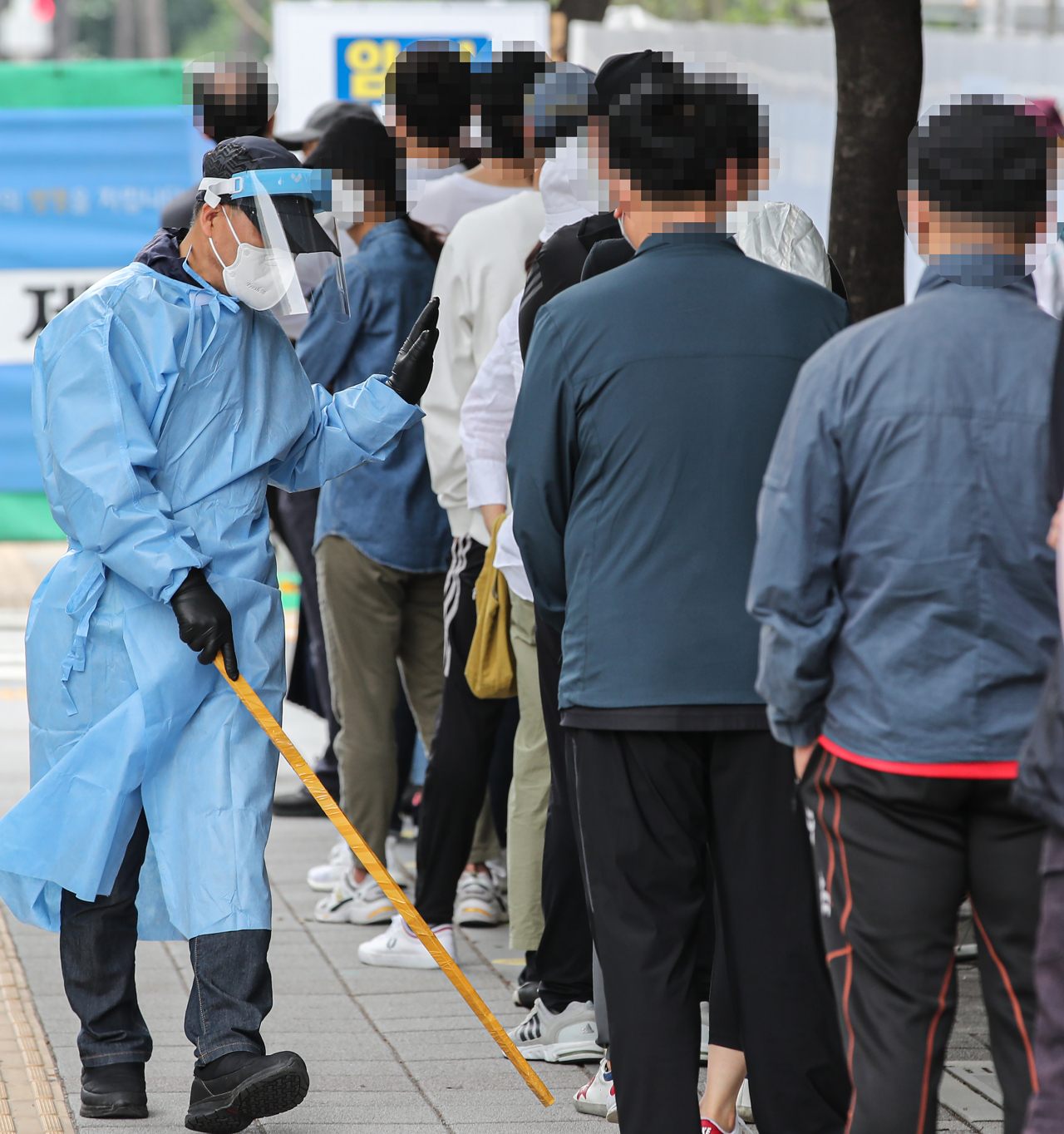 29일 오전 서울시 송파구 보건소 선별진료소에서 관계자가 검사를 받기 위해 줄지어 서 있는 시민들에게 거리 두기를 안내하고 있다. 연합뉴스