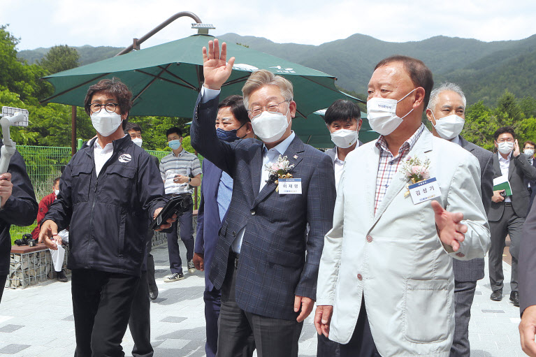 이재명 경기도지사(가운데)가 26일 경기도 가평군 북면 용소폭포에서 열린 경기도 청정계곡 생활SOC 준공식에서 정비된 계곡을 찾은 방문객들에게 손을 흔들고 있다. [연합]