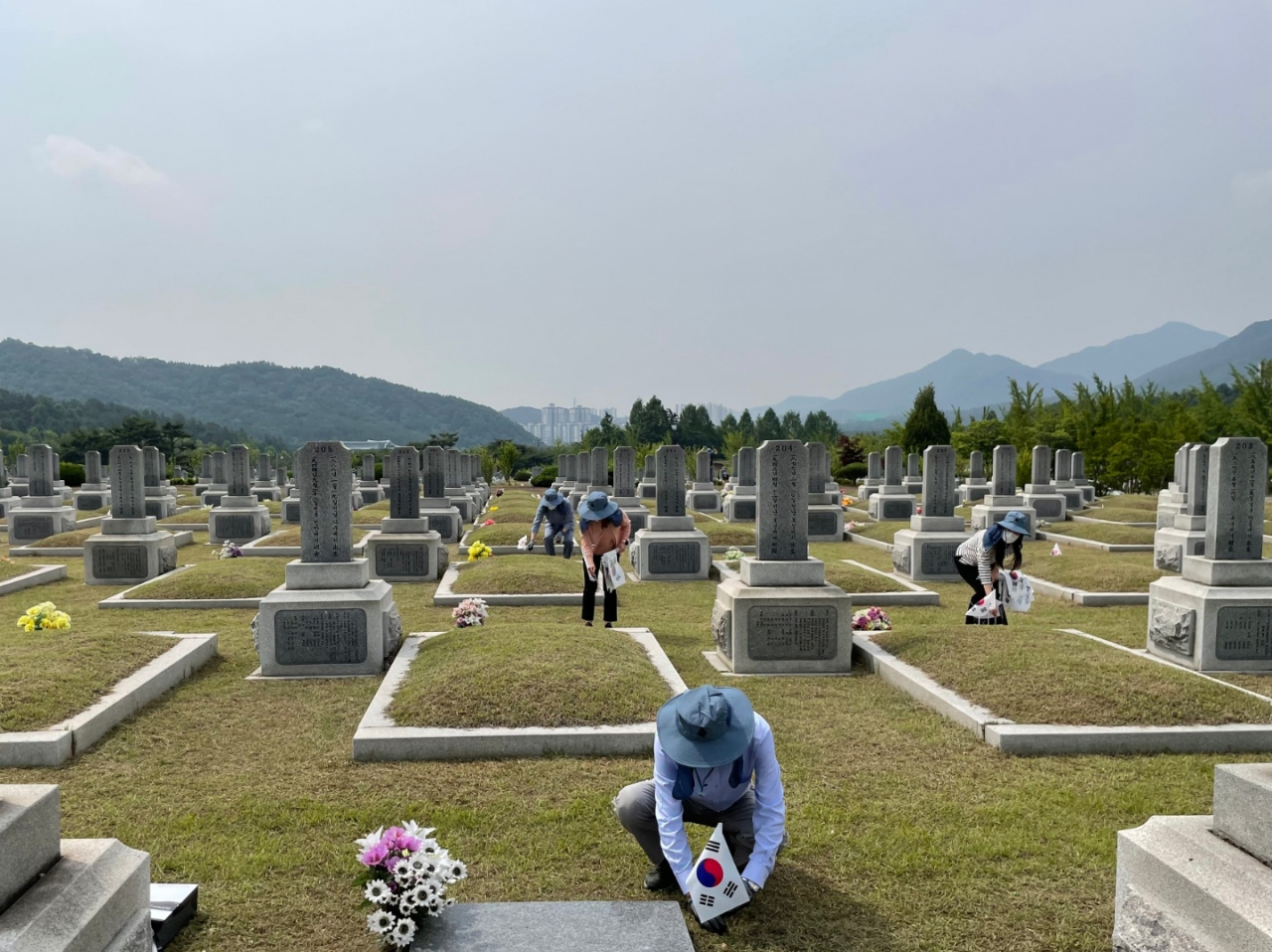UST 임직원 20명이 대전 현충원을 찾아 묘역에 태극기를 꽂고 있다.[UST 제공]
