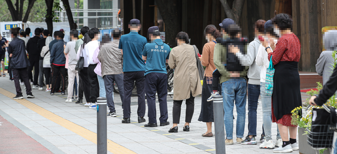 신종 코로나바이러스 감염증(코로나19) 신규 확진자가 연이틀 500명대를 기록한 지난 달 29일 오전 서울시 송파구 보건소 선별진료소를 찾은 시민들이 검사를 받기 위해 줄지어 서 있다. [연합]