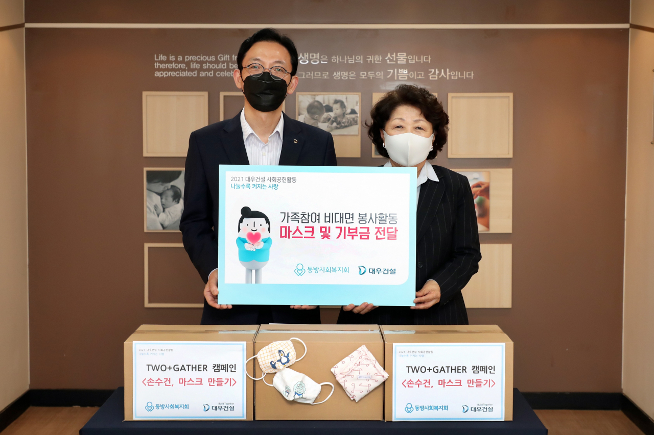 대우건설은 지난 2일 임직원과 가족이 참여해 제작한 마스크와 기부금을 동방사회복지회에 전달했다. 사진은 전달식에 참여한 강기남 대우건설 관리지원실장(왼쪽)과 김진숙 동방사회복지회 회장. [대우건설 제공]