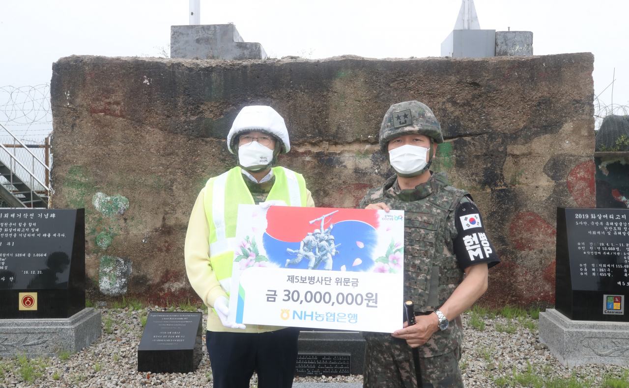 이성희(왼쪽) 농협중앙회장이 3일 강원 철원 비무장지대(DMZ)내 화살머리고지와 백마고지 유해발굴작전 현장을 방문해 제5보병사단에 위문금을 전달한 후 기념촬영을 하고 있다.[농협중앙회 제공]