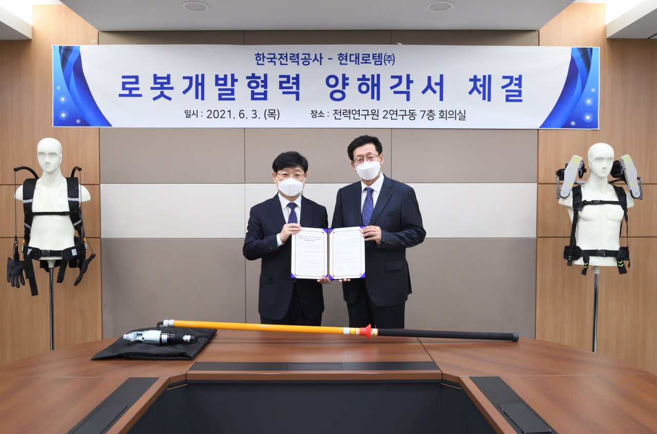 지난 3일 대전에 있는 한전 전력연구원에서 송기욱(왼쪽) 한전 전력연구원 융복합프로젝트연구소장과 안경수(오른쪽) 현대로템 디펜스솔루션사업본부장이 기념사진을 촬영하고 있다. [현대로템 제공]