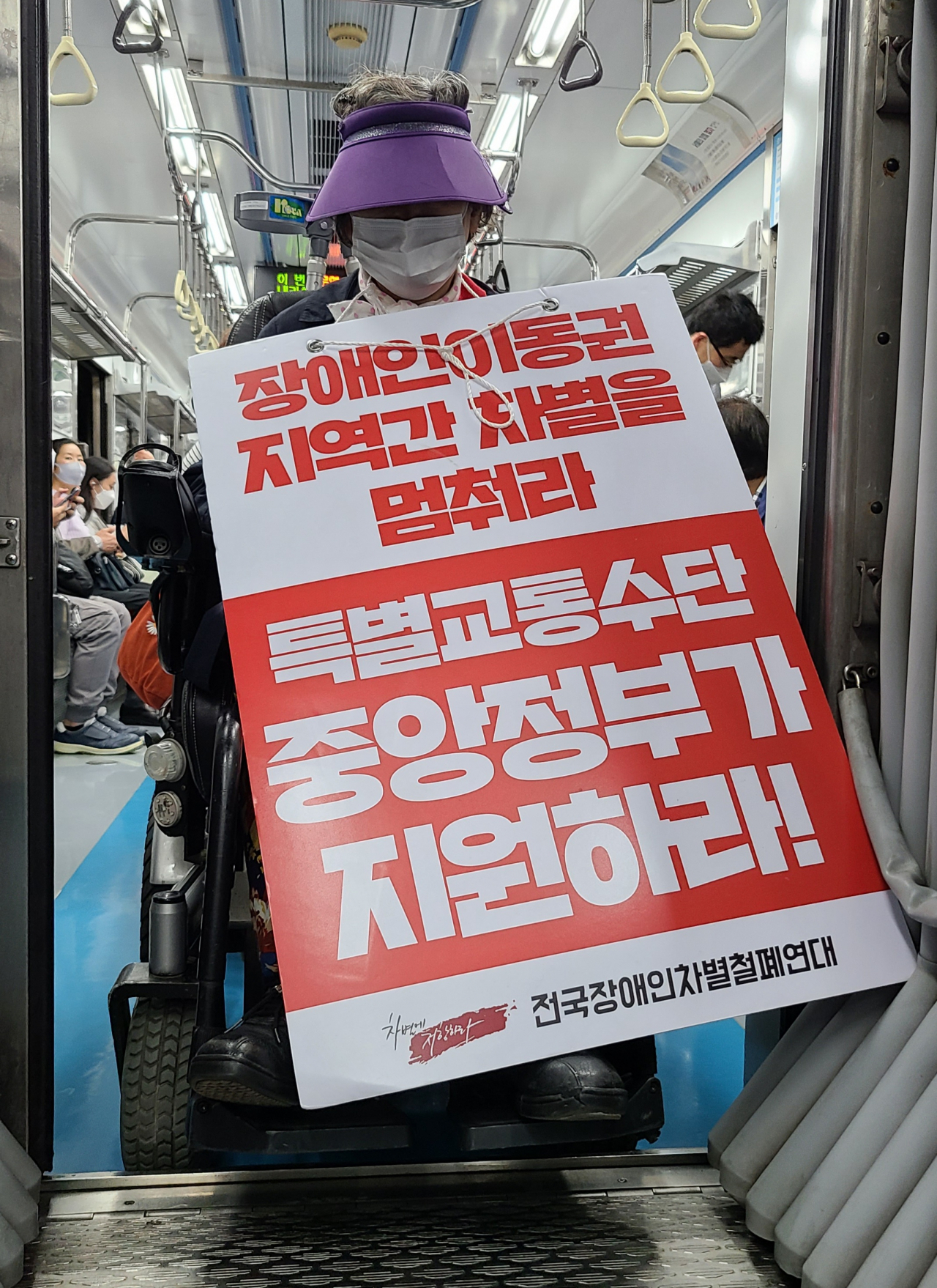 지난 4일 오후 서울 지하철 4호선에서 한 장애인이 정부가 장애인을 위한 특별교통수단을 지원하라는 내용의 피켓을 들고 있다. [연합]