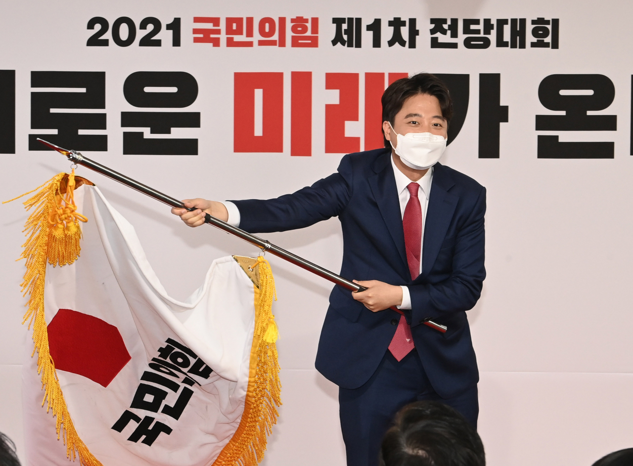 국민의힘 이준석 새 대표가 11일 서울 여의도 중앙당사에서 열린 전당대회에서 당기를 흔들고 있다. [연합]
