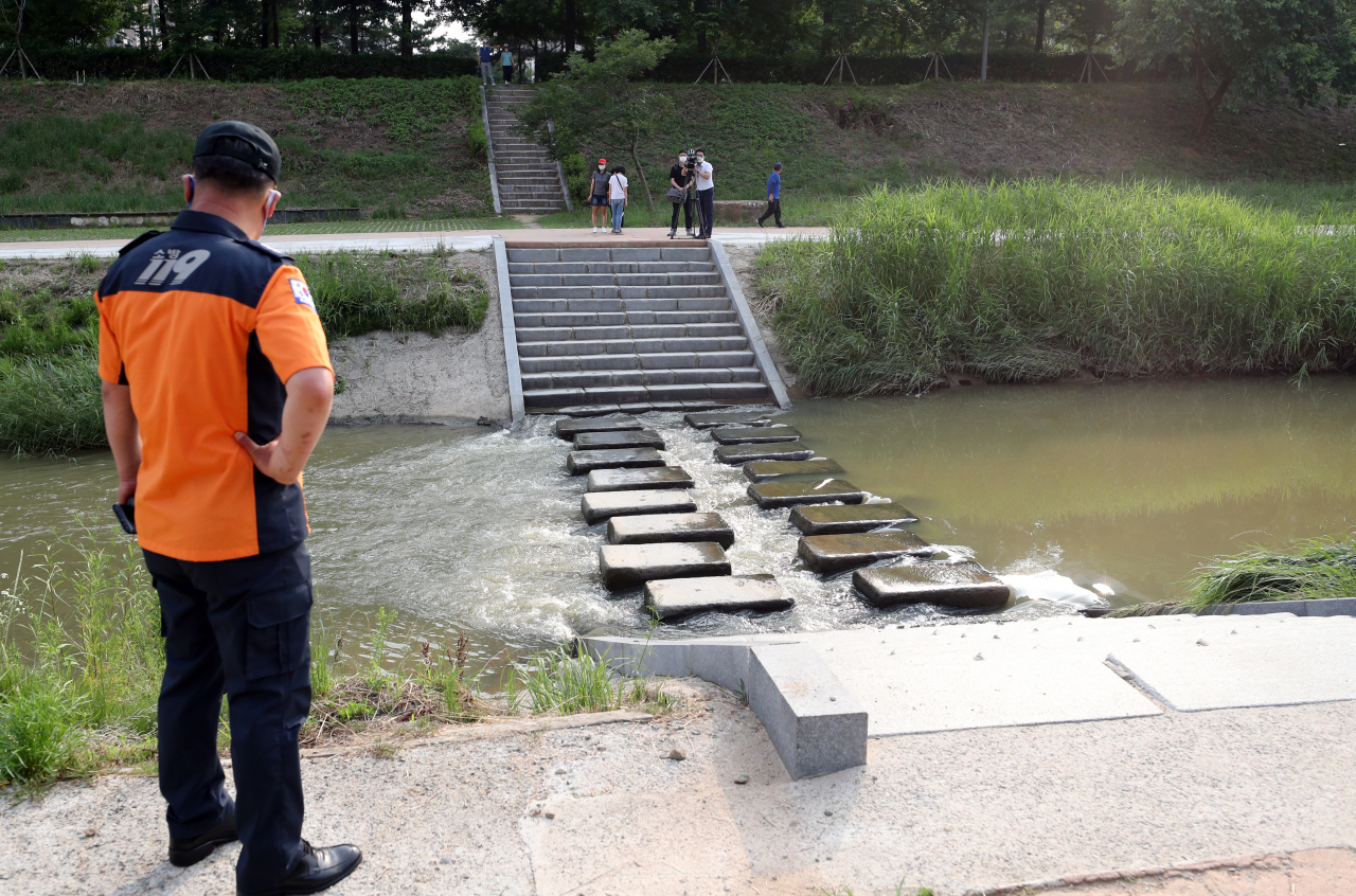 12일 오후 광주 광산구 수완동 풍영정천 한 징검다리에서 소방대원이 초등학생 2명이 빠진 사고 현장을 살펴보고 있다. 이날 징검다리 주변에서 물총놀이를 하던 초등 3학년 학생 2명이 물에 빠져 1명은 숨지고 1명은 위독하다. [연합]
