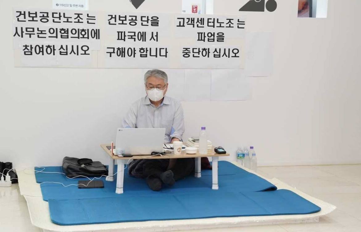 김용익 건강보험공단 이사장이 14일 오전 강원 원주혁신도시 내 건보공단 본부 로비에서 단식을 하고 있다. 김 이사장은 작은 테이블을 둔 채 업무를 보고 있으며, 단식 종료 기한은 정해지지 않은 것으로 알려졌다. [건강보험공단 제공]