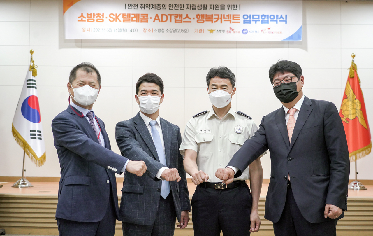 지난 14일 세종시 소방청 본부에서 진행된 협약식에서 (왼쪽부터) 박대호 행복커넥트 상임이사, 정영철 ADT캡스 운영본부장, 배덕곤 소방청 119구조구급국장, 이준호 SK텔레콤 ESG사업담당이 기념 사진을 찍고 있다. [SK텔레콤 제공]
