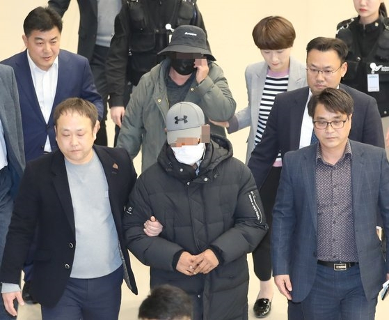 2019년 마이크로닷 부모가 인천국제공항을 통해 귀국한 뒤 경찰에 체포돼 공항을 빠져나가고 있다. [연합]