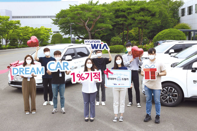 현대위아 직원들이 22일 경상남도 창원시 성산구 현대위아 본사에서 지역 복지기관에 선물할 ‘현대위아 드림카’와 기념사진을 찍고 있다. [현대위아 제공]