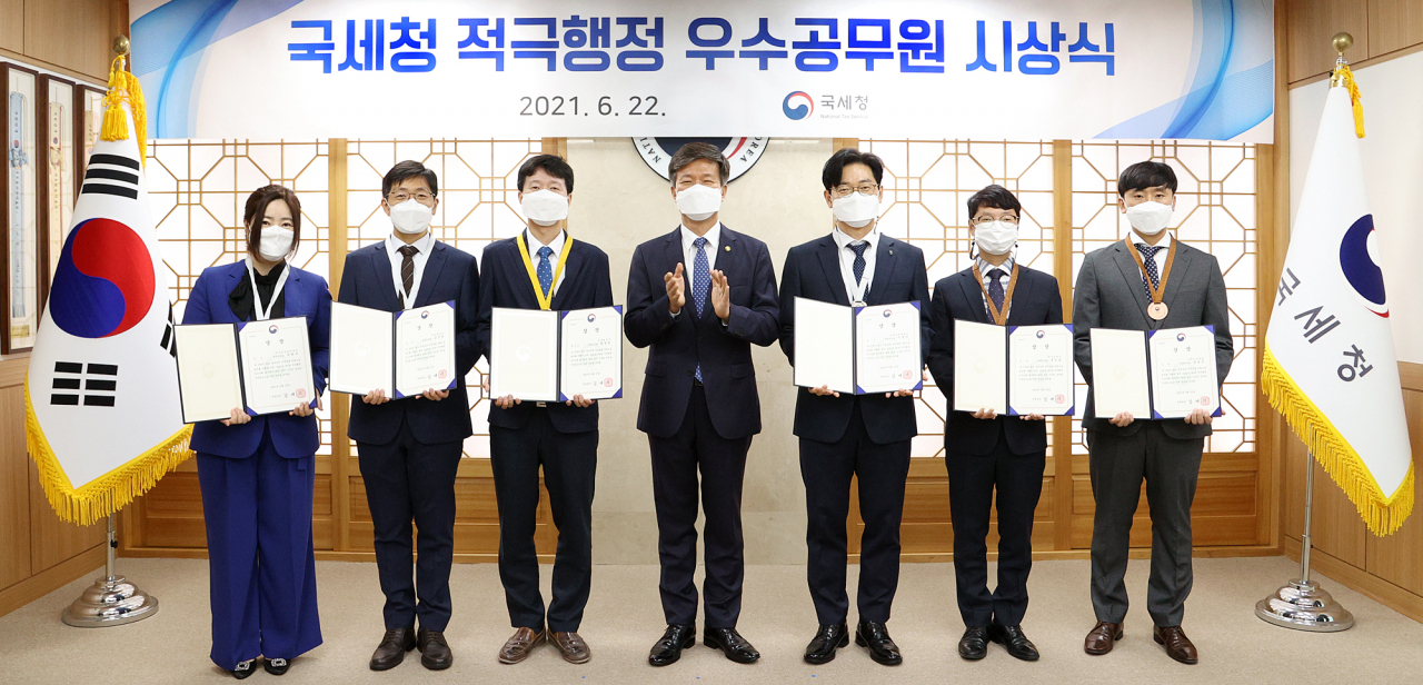 김대지 국세청장(가운데)이 22일 적극행정 우수공무원을 선정해 표창한 뒤 기념촬영을 하고 있다. 왼쪽부터 박현주 사무관, 김상동 조사관, 황병광 조사관, 김대지 국세청장, 이종영 조사관, 윤정호 조사관, 남봉근 조사관. [국세청 제공]
