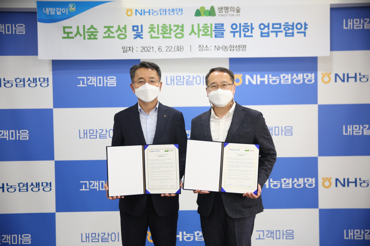 NH농협생명 김인태(왼쪽) 대표이사와 (사)생명의숲 김인호 공동대표가 업무협약서를 들고 포즈를 취하고 있다.