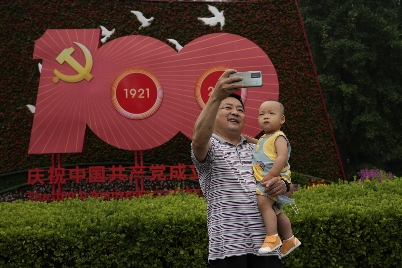 중국 베이징에서 중국 공산당 100주년을 앞두고 한 남성이 아기와 함께 기념 촬영을 하고 있다. [AP]