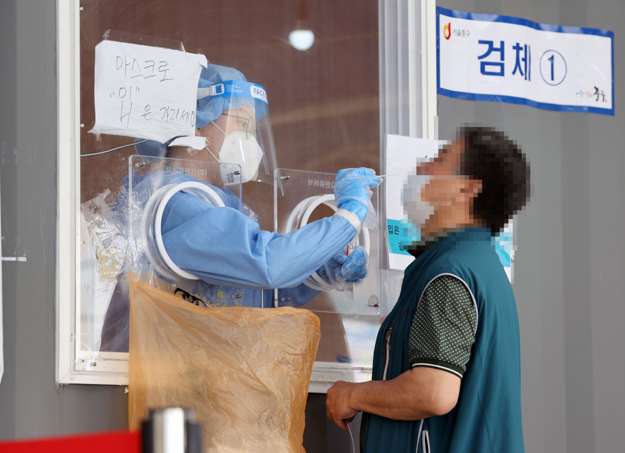 27일 서울역 광장에 마련된 신종 코로나바이러스 감염증(코로나19) 임시 선별검사소에서 의료진이 검체를 채취하고 있다. 이날 신규 확진자 수는 614명으로 전날보다 50여명 줄었으나 지난 23일 이후 닷새 연속 600명대를 기록했다. 연합뉴스