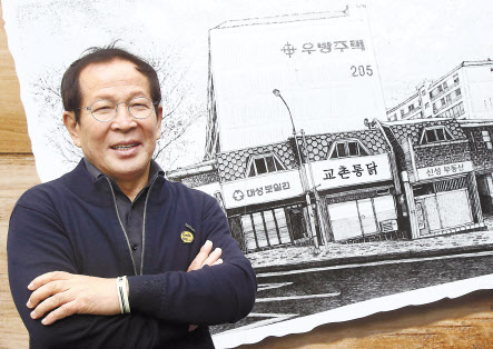 지난 1991년 10평 남짓한 작은 가게에서 지금의 교촌에프앤비를 일군 권원강 창업주가 전 가맹점주에게 100억원 상당의 주식을 증여하기로 했다. 사진은 권 창업주가 교촌치킨 1호점 일러스트 앞에서 포즈를 취하고 있는 모습이다. [교촌에프앤비 제공]