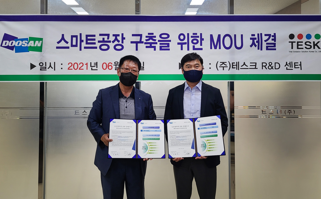 이용진 두산인프라코어 구매총괄 전무(오른쪽)가 황정상 ㈜테스크 대표와 스마트공장 구축 지원 양해각서를 체결한 후 기념사진을 촬영하고 있다.[두산인프라코어 제공]