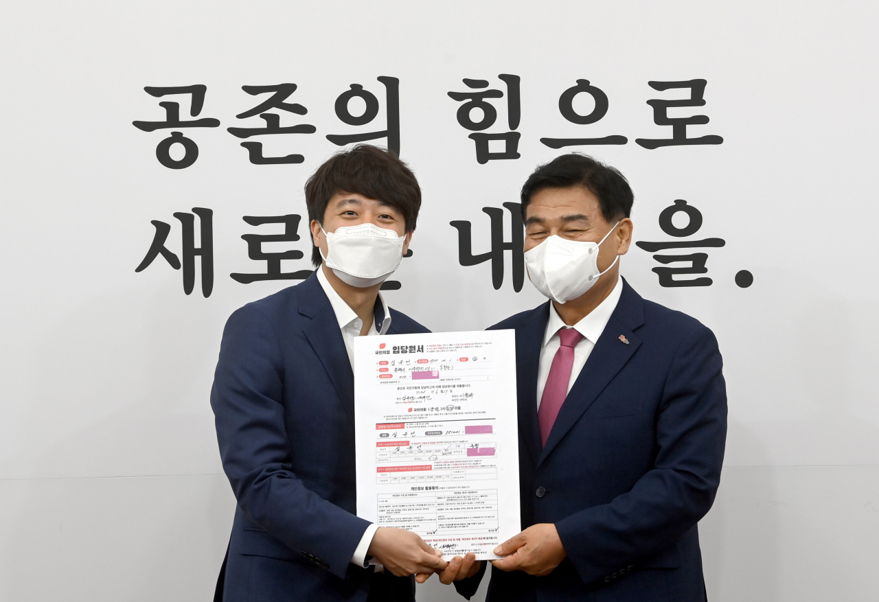 이준석 국민의힘 대표(왼쪽)가 1일 서울 여의도 국회에서 열린 최고위원회의에 앞서 일괄복당 1호인 심규언 무소속 동해시장의 입당서를 받고 있다. [연합]
