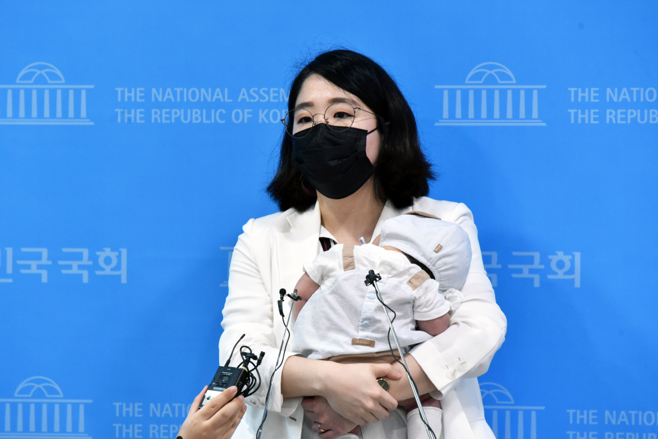 출산 뒤 아기와 첫 출근한 기본소득당 용혜인 의원이 5일 서울 여의도 국회 소통관에서 기자회견을 마친 뒤 아기를 안고 취재진의 질문에 답하고 있다. [연합]