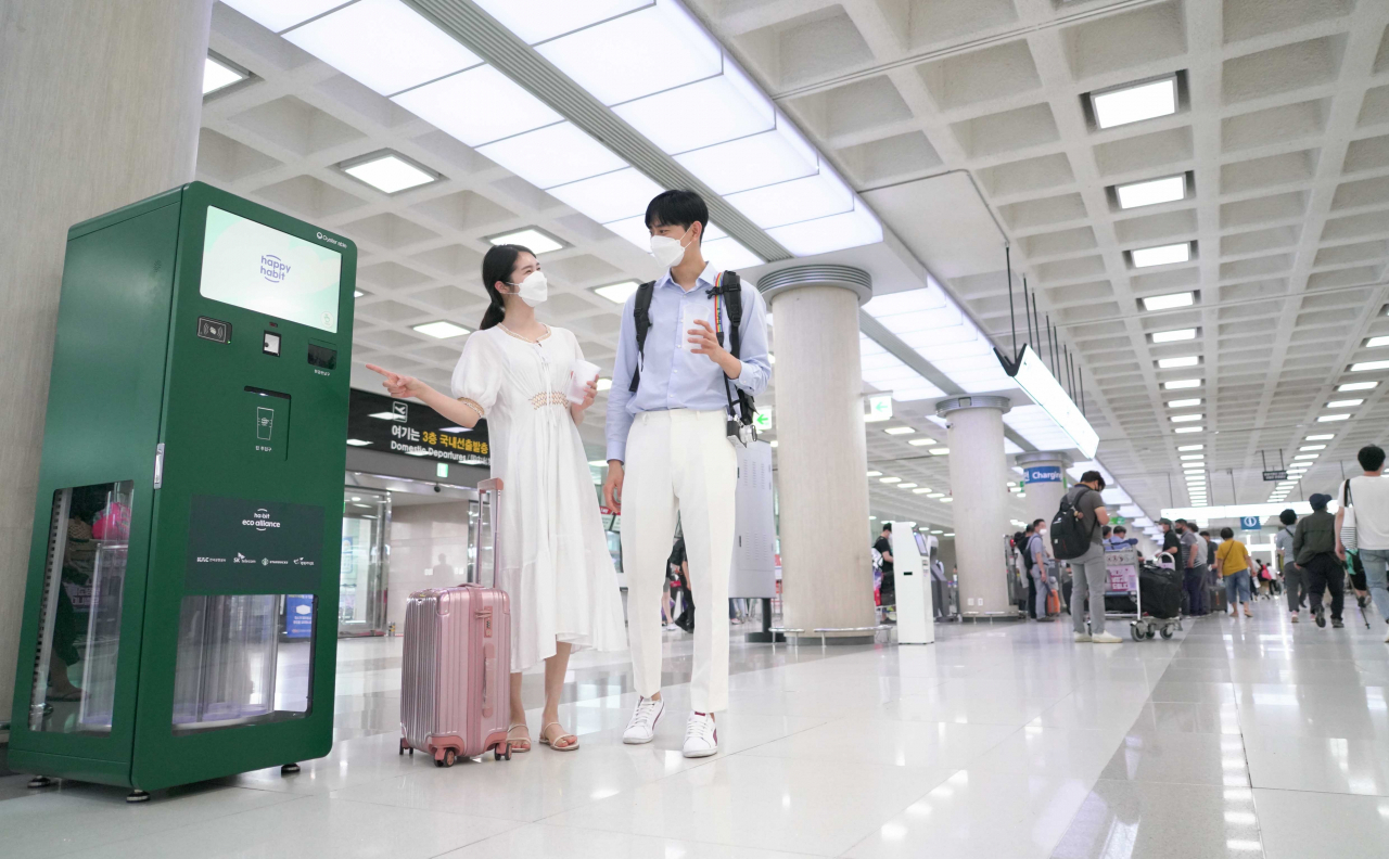 제주 관광객들이 제주국제공항 안에 설치된 무인 다회용컵 반납기를 통해 사용을 마친 컵을 반납하고 있다. [SK텔레콤 제공]