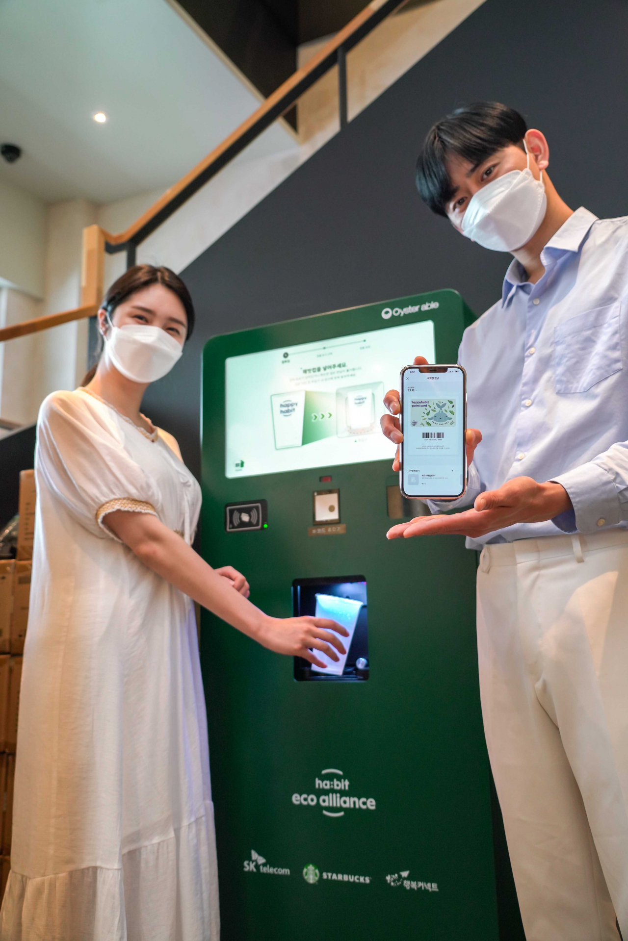 이용자들이 스타벅스 매장에 설치된 무인 다회용컵 반납기와 해피해빗 앱을 이용해 다회용컵을 반납하고 있다. [SK텔레콤 제공]
