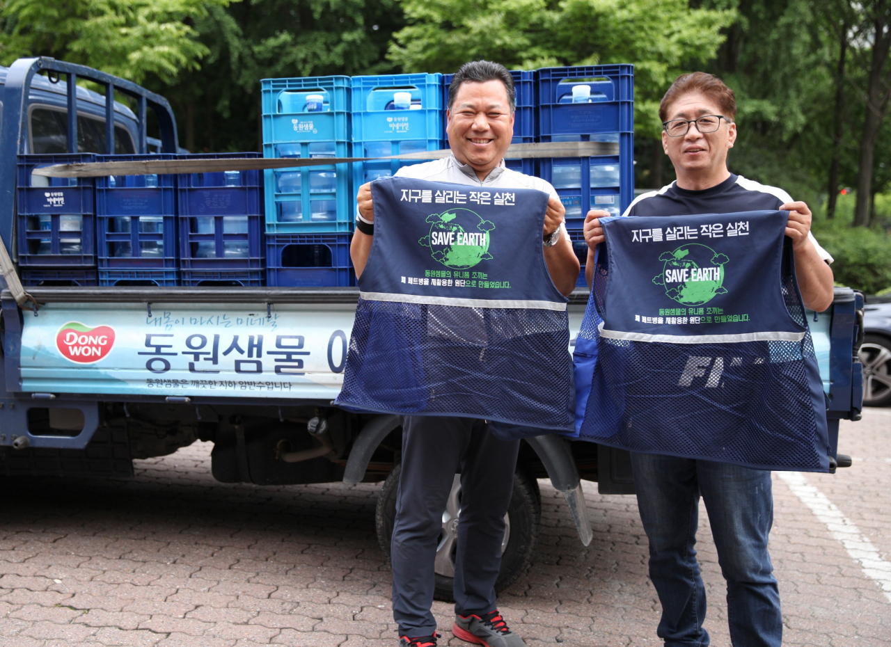 동원샘물 대리점 직원들이 폐페트병으로 만들어진 친환경 유니폼을 들고 기념 사진을 촬영하고 있다. [동원F&B 제공]