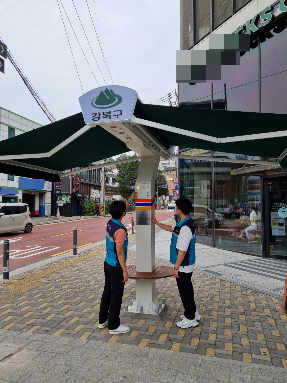 강북구 관계공무원이 지난달 30일 스마트 그늘막이 설치된 모습을 살펴보고 있다. [강북구 제공]