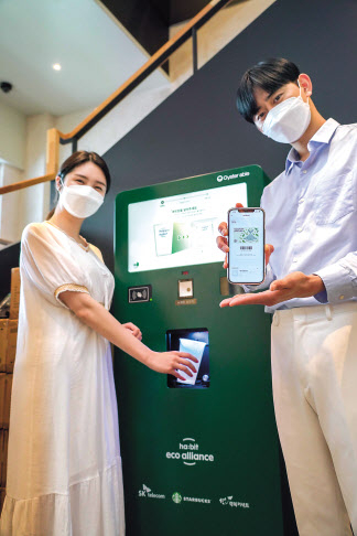 이용자들이 스타벅스 매장에 설치된 무인 다회용컵 반납기와 해피해빗 앱을 이용해 다회용컵을 반납하고 있다. [SK텔레콤 제공]