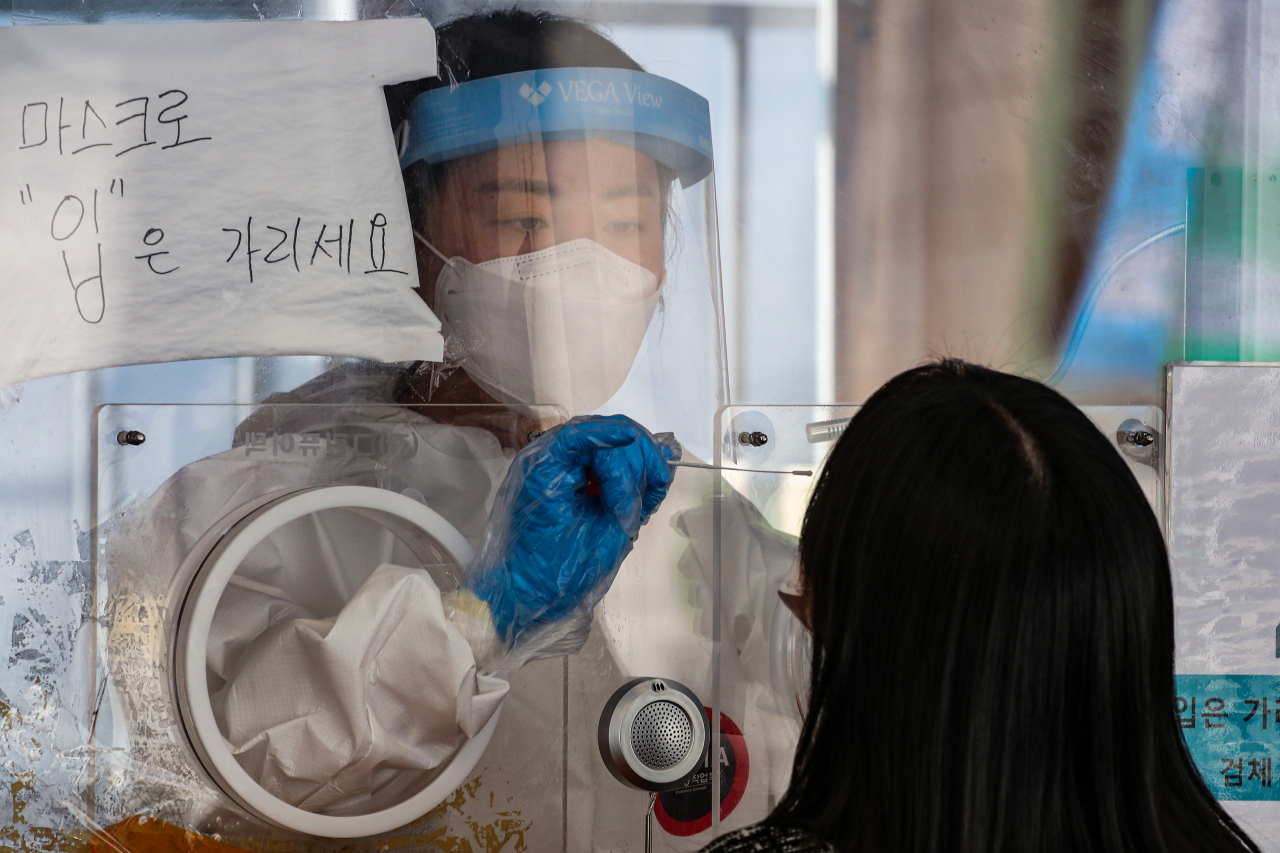 6일 오전 서울 중구 서울역에 마련된 코로나19 선별검사소에 관계자가 시민에게 채취하고 있다.코로나19 신규 확진자는 746명을 기록해 1주일 연속 700명 이상을 기록했다. [연합]