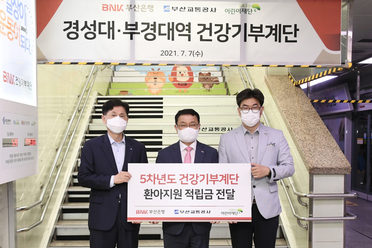 BNK부산은행은 7일(수) 오후, 부산지하철 2호선 경성대·부경대역 승강장에서 ‘BNK건강기부계단’ 적립금 2000만원을 초록우산어린이재단 부산지역본부에 전달했다.(오른쪽부터 노희헌 초록우산어린이재단 부산지역본부장, BNK부산은행 손강 경영전략그룹장, 이동렬 부산교통공사 경영본부장) [부산은행 제공]