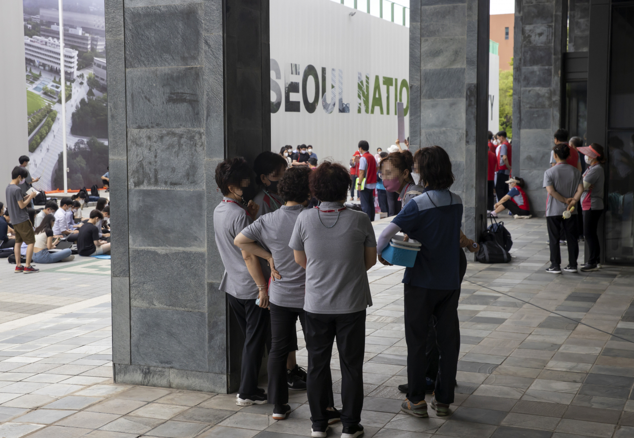 지난 7일 서울 관악구 서울대 관악캠퍼스에서 열린 ‘서울대학교 청소 노동자 조합원 사망 관련 서울대학교 오세정 총장 규탄 기자회견’에서 이 대학 노동자들이 멀리서 기자회견을 지켜보고 있다. [연합]