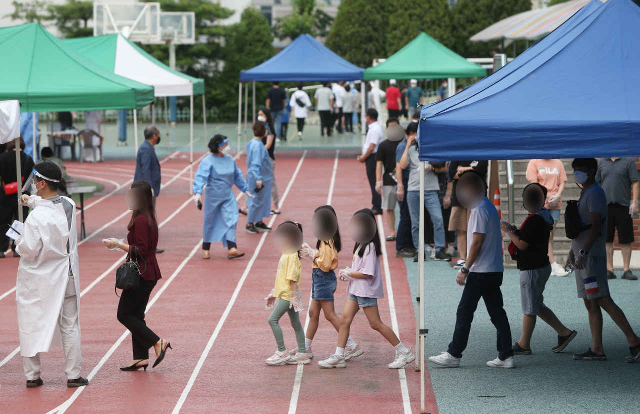 인천 미추홀구 인주초등학교 연관 코로나19 확진자의 70%가량인 34명이 2개 학급에서 발생한 것으로 파악됐다. 인주초 일대에서 코로나19 검사를 받기 위해 모여든 시민들과 의료진. [연합]