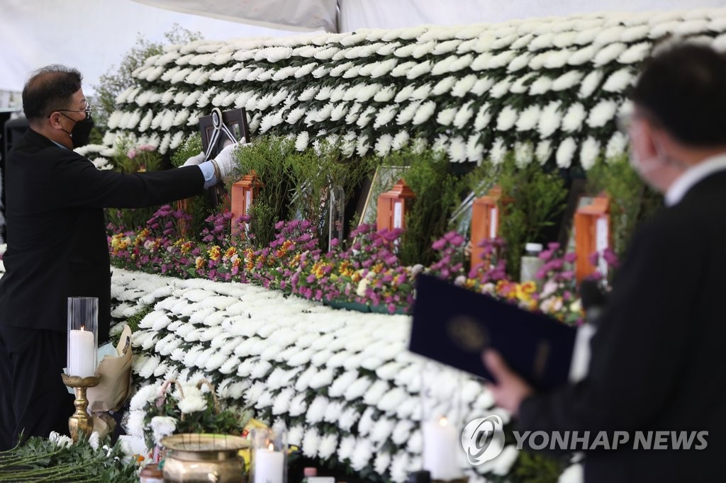 12일 오전 광주 동구청 주차장에 마련된 철거건물 붕괴참사 합동분향소에서 장례지도사가 희생자 영정을 내리고 있다.