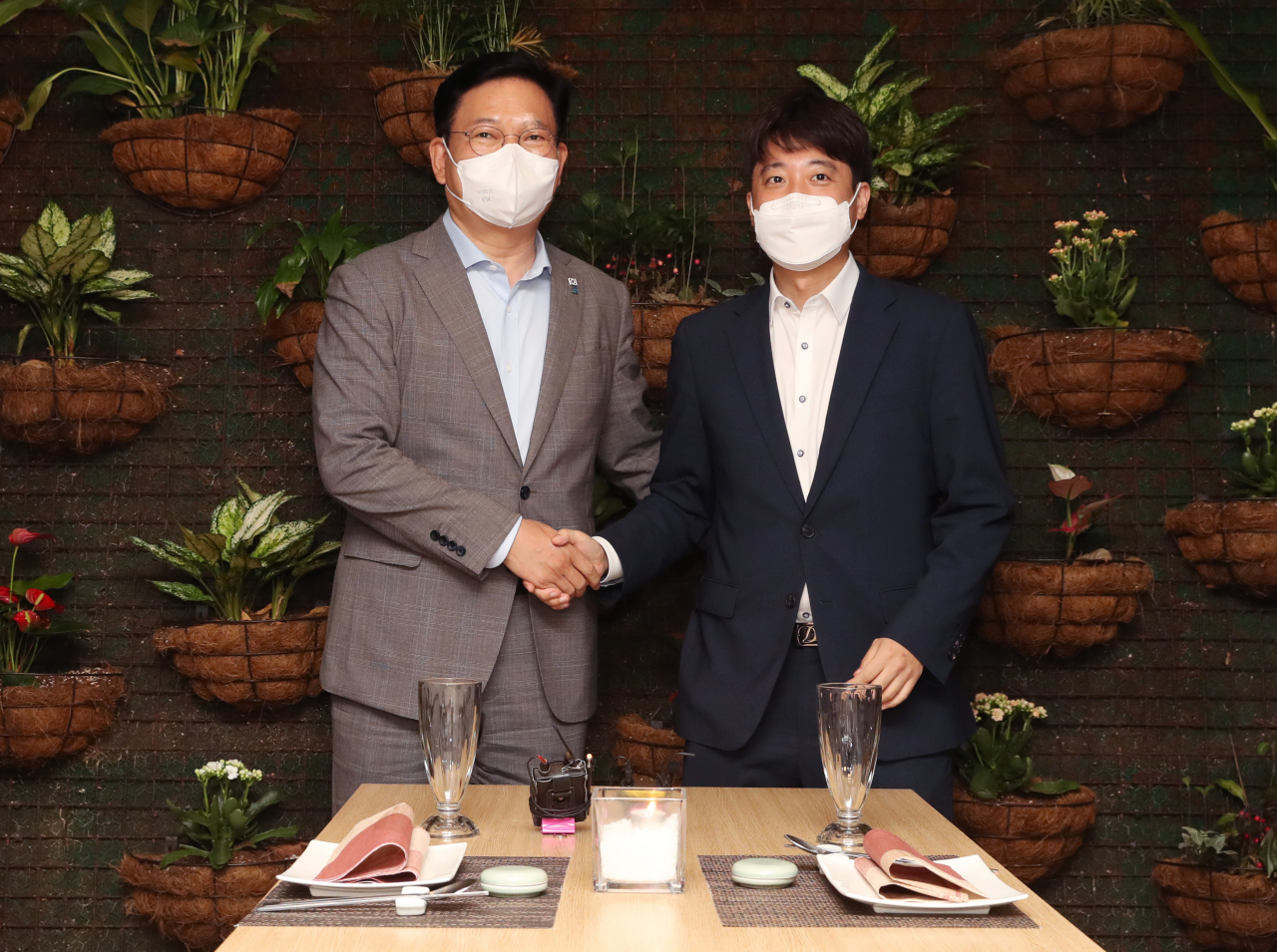더불어민주당 송영길 대표(왼쪽)와 국민의힘 이준석 대표가 12일 서울 여의도의 한 식당에서 열린 만찬 회동에서 악수하고 있다. [연합]