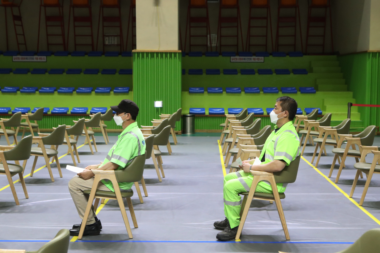 This photo shows members of the essential workforce waiting at a vaccination clinic in Seoul on Tuesday. (Yonhap)