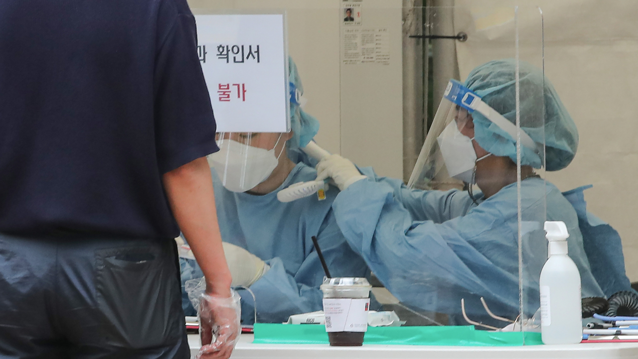 신종 코로나바이러스 감염증(코로나19) 신규 확진자가 1주일째 1천 명 이상 기록 중인 13일 오후 서울 마포구 홍대 거리 내 홍익문화공원에 설치된 마포구 임시선별검사소에서 한 관계자가 업무중인 동료의 목에 휴대용 선풍기를 걸어주고 있다. [연합]
