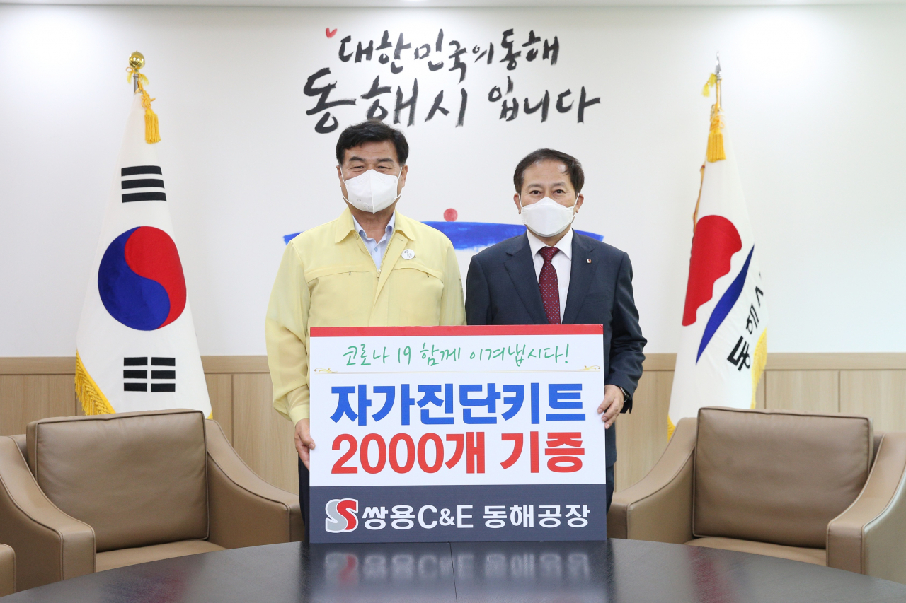 심규언(왼쪽) 동해시장과 원용교 쌍용C&E 동해공장장이 코로나19 자가진단키트 전달 뒤 기념촬영을 하고 있다. [쌍용C&E 제공]