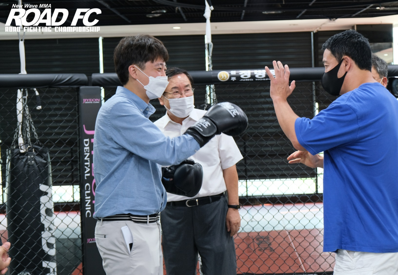 국힘 이준석 대표가 14일 강원도 지역 실내체육인과 가진 간담회에서 스파링 글러브를 낀 채 펀칭 동작을 취해 보고 있다. 이 대표의 펀치를 맨손으로 받아주는 시늉을 하고 있는 이는 격투기대회 로드FC 회장인 정문홍 씨다. [로드FC 제공]