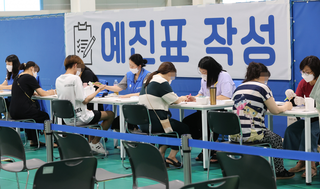 14일 오전 서울 은평구 제2예방접종센터에서 시민들이 백신 접종을 받기 전 예진표를 작성하고 있다. 연합뉴스