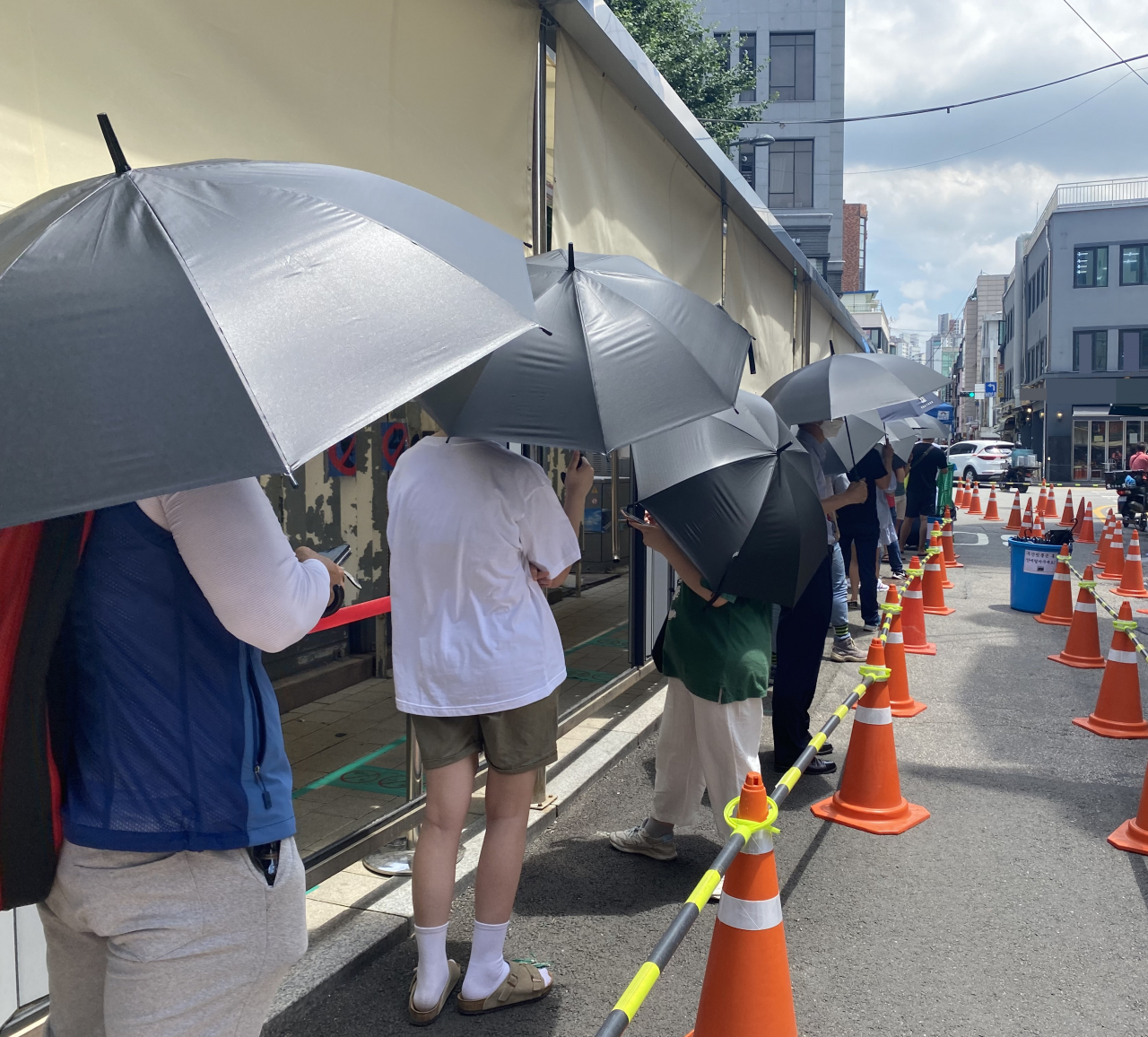 지난 14일 오후 1시께 서울 중구 보건소에 설치된 코로나19 선별진료소. 햇볕을 막기 위해 비치된 검은 우산을 쓴 채 대기하고 있는 시민들이 보인다. 해당 우산은 선별진료소 측에서 대기자들이 더위를 피할 수 있도록 마련한 것이다. 주소현 기자