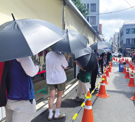 지난 14일 오후 1시께 서울 중구 보건소에 설치된 코로나19 선별진료소. 햇볕을 막기 위해 비치된 검은 우산을 쓴 채 대기하고 있는 시민들이 보인다. 해당 우산은 선별진료소 측에서 대기자들이 더위를 피할 수 있도록 마련한 것이다. 주소현 기자