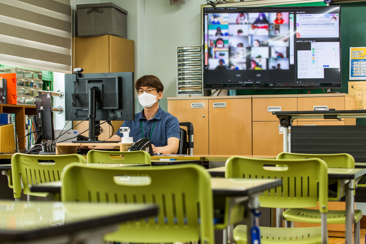 코로나19 확산에 따른 수도권 사회적 거리두기 4단계 격상으로 수도권 학교들이 전면 원격수업에 들어간 14일 오전 서울 성동구 무학초등학교 5학년 교실에서 선생님이 온라인 수업을 진행하고 있다. [연합]