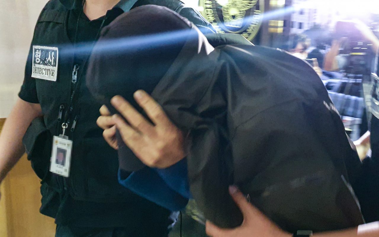 서울 마포의 한 오피스텔에서 40대 남성을 살해한 혐의를 받는 피의자 A씨가 15일 오후 서울 마포구 마포경찰서로 압송되고 있다. 피의자 A씨는 이날 오전 경북 경산에서 검거돼 호송차를 타고 마포서에 도착했다. [연합]