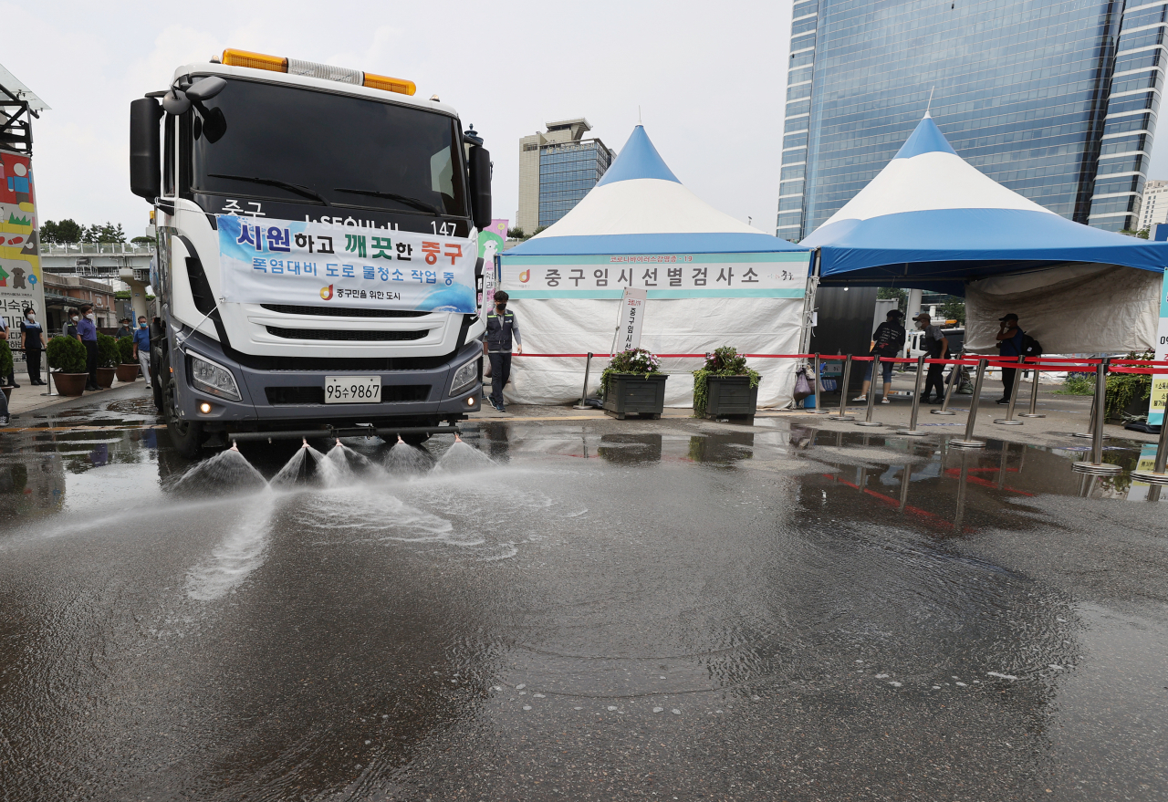 지난 15일 오후 서울 중구 서울역광장에 설치된 중구 임시선별검사소 앞에서 살수차가 더위를 식히기 위해 물을 뿌리고 있다. [연합]