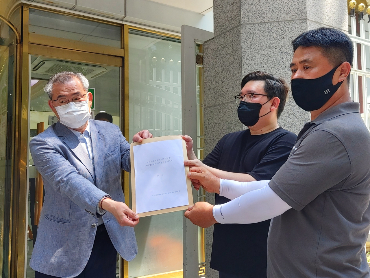 16일 정부서울청사에서 코로나19 대응 전국자영업자비상대책위원회 김기홍(왼쪽)·경기석 공동대표가 국무총리비서실 민정실의 김창훈 민원과장에 질의서를 전달하고 있다. 김희량 수습기자