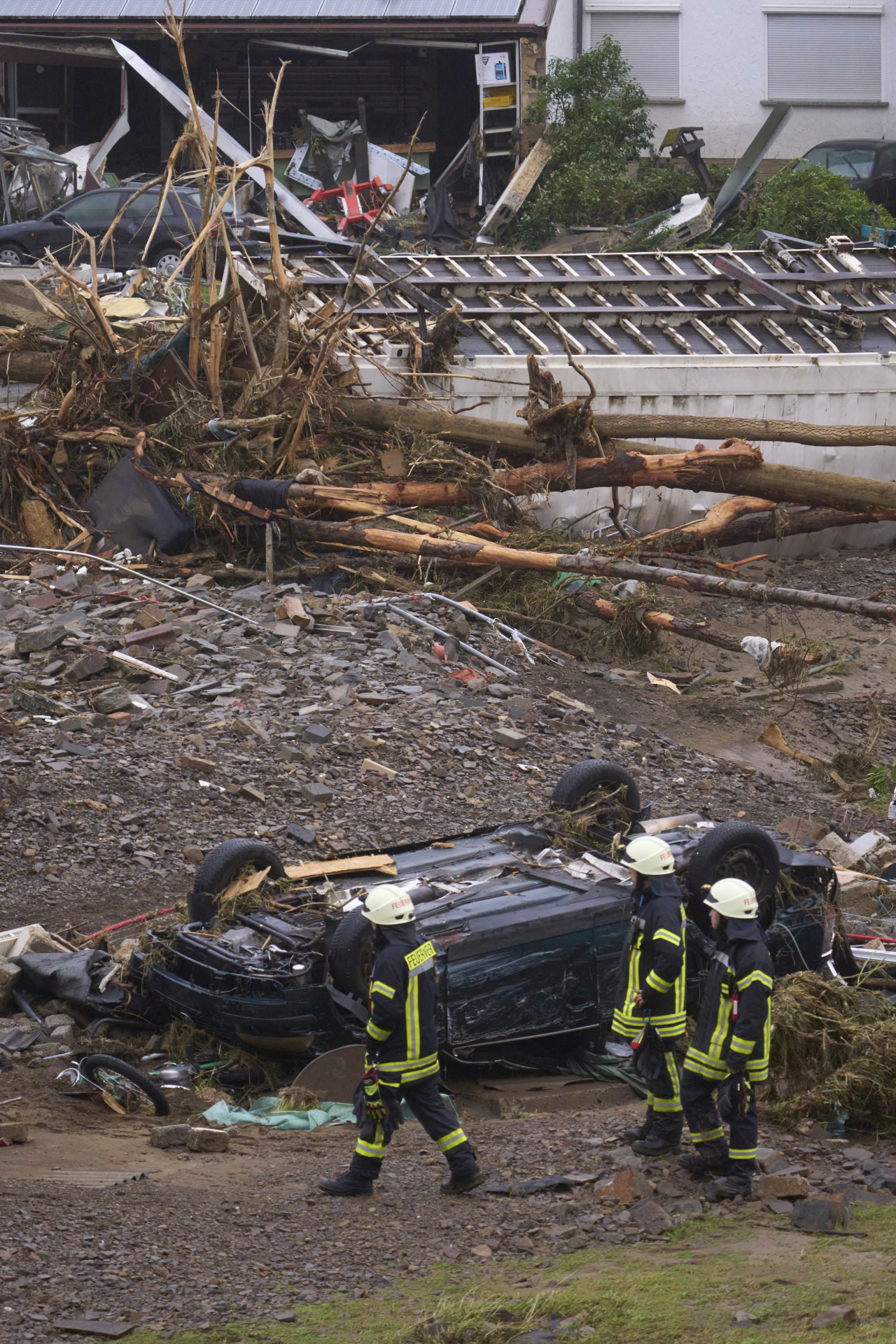 Firefighters walk past a destroyed car in the community of Schuld, Germany, Friday, July 16, 2021. Heavy rains caused mudslides and flooding in the western part of Germany. Multiple have died and dozens are missing as severe flooding in Germany and Belgium turned streams and streets into raging, debris-filled torrents that swept away cars and toppled houses. (AP-Yonhap)