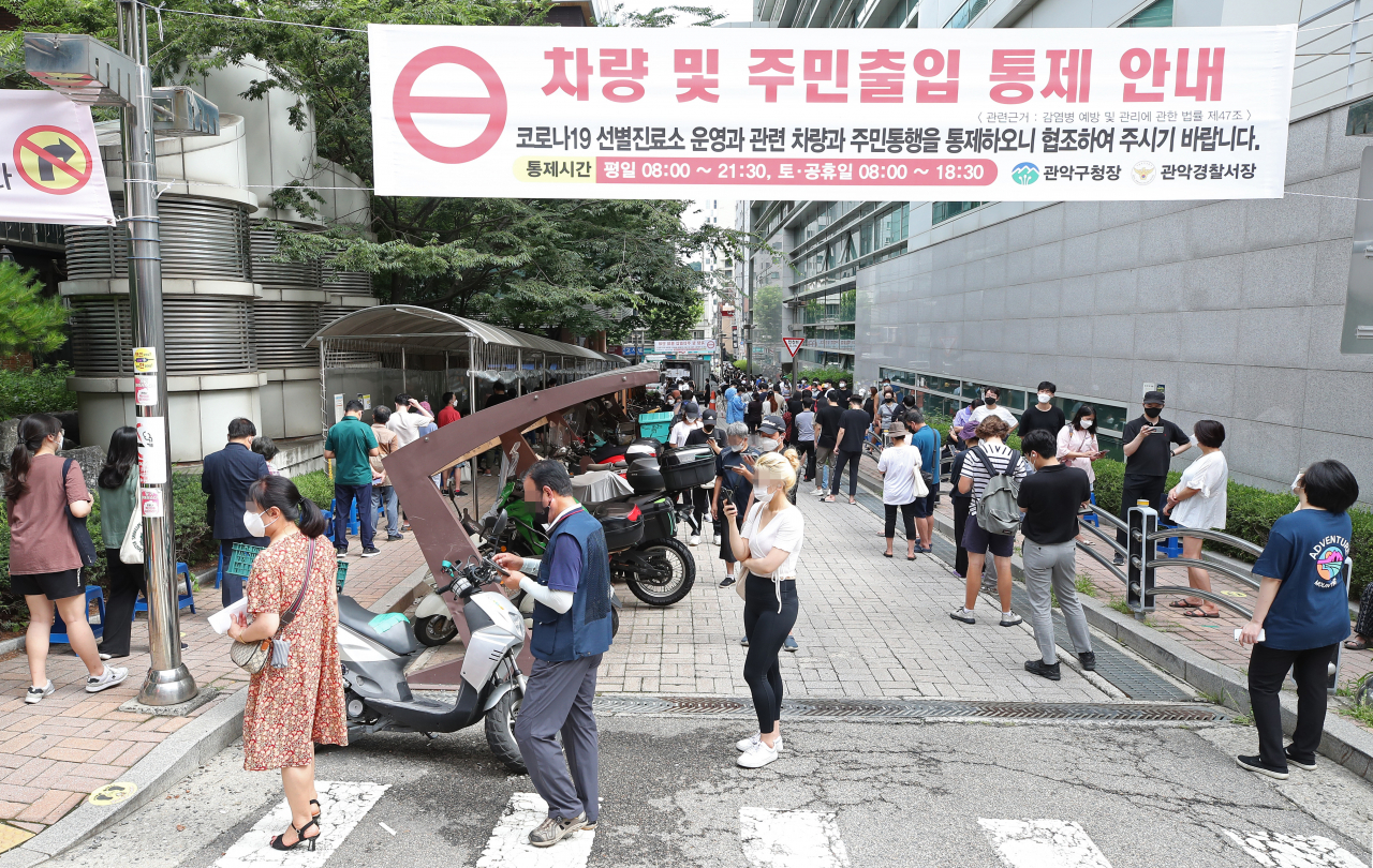 국내 신종 코로나바이러스감염증(코로나19) 신규 확진자 수가 13일째 네자릿수를 기록하고 있는 19일 오전 서울 관악구 보건소에 마련된 선별진료소를 찾은 시민들이 검사를 위해 구청과 보건소 주위를 둘러 줄 서 있다. 중앙방역대책본부에 따르면 이날 신규 확진자 수는 1천252명으로 지난 7일 이후 13일째 네자릿수를 기록했다. 또한 이는 일요일 확진자 기준으로 가장 많은 수치이다. 연합뉴스