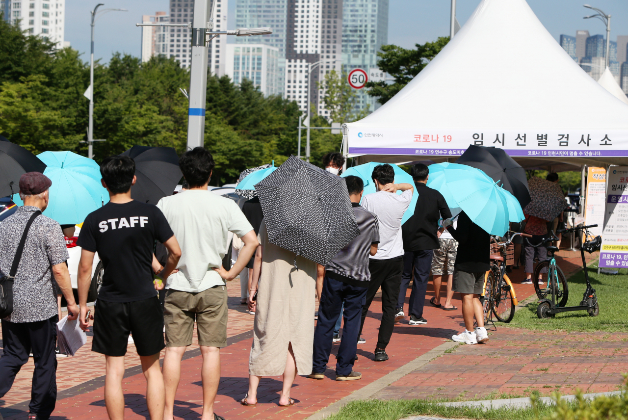 폭염경보가 내려진 21일 인천시 연수구 송도 미추홀타워 임시 선별검사소에서 시민들이 코로나19 검체 검사를 받기 위해 대기하고 있다. [연합]