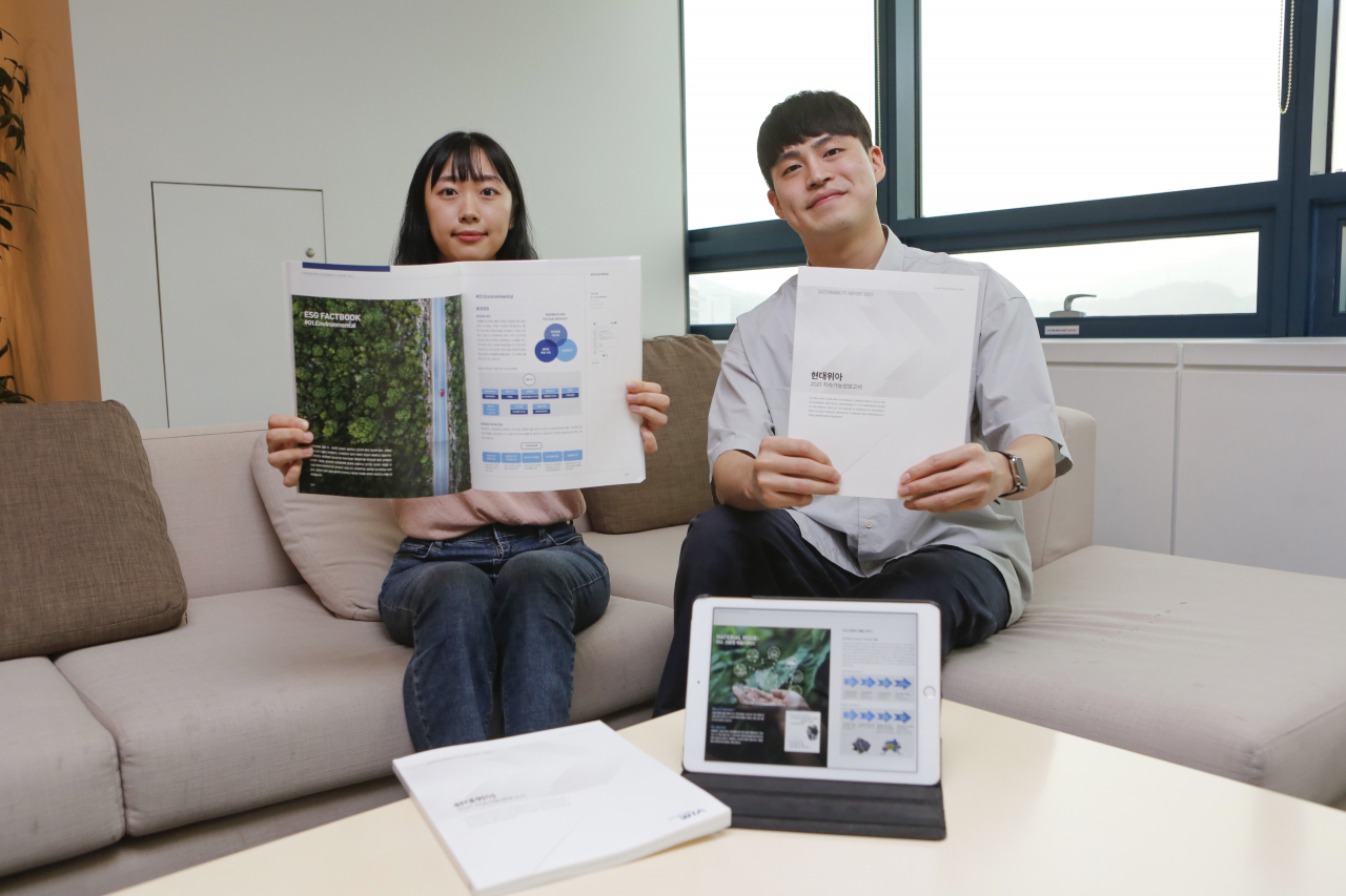 현대위아 직원들이 23일 경기도 의왕시 현대위아 의왕연구소에서 ‘현대위아 2021 지속가능성보고서’를 들어 보이고 있다. [현대위아 제공]