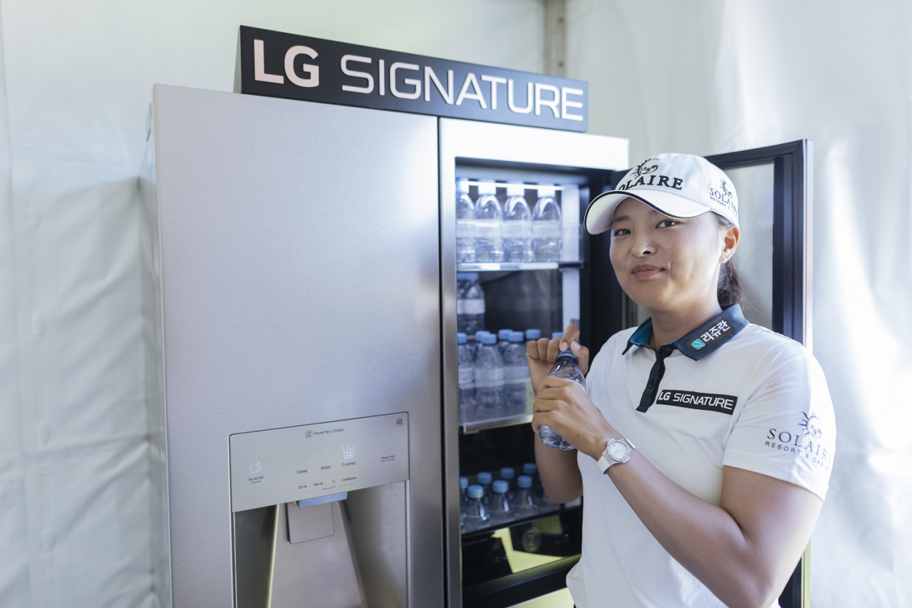 프랑스 에비앙리조트골프클럽에서 열리는 아문디에비앙챔피언십 1번홀 내 LG 시그니처 체험존에서 고진영 선수가 냉장고 안의 에비앙 생수를 꺼내 마시며 직접 제품을 체험해보고 있다.[LG전자 제공]